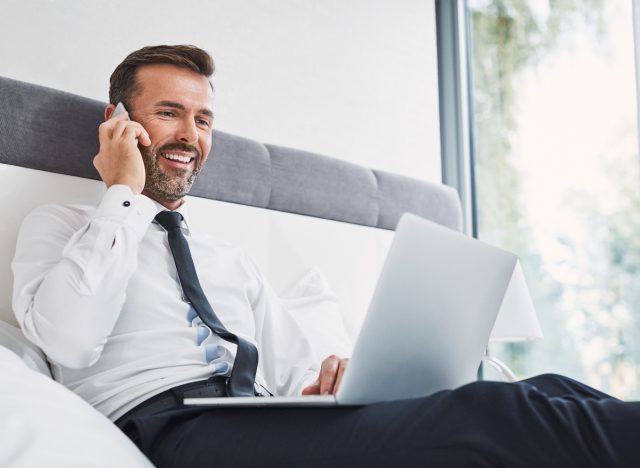 man working from bed taking a call