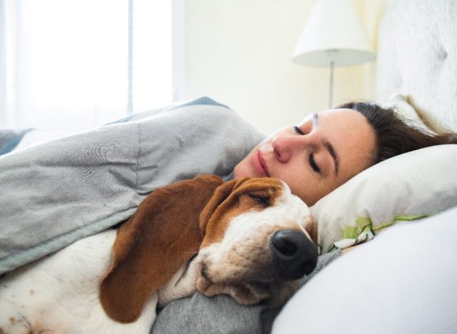 woman sleeping peacefully in bed with her dog