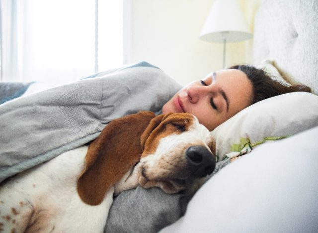woman sleeping peacefully in bed with her dog