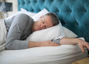 man sleeping peacefully in bright bedroom