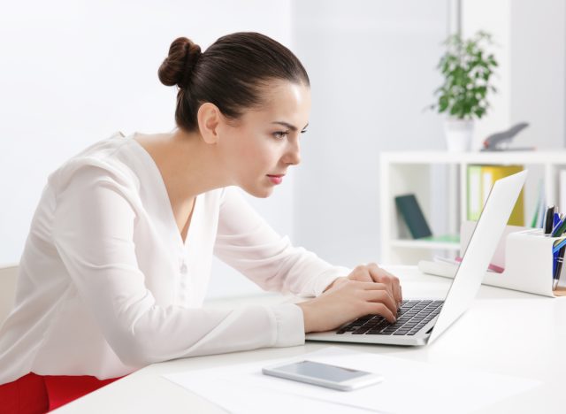 woman with incorrect posture tying on laptop at desk