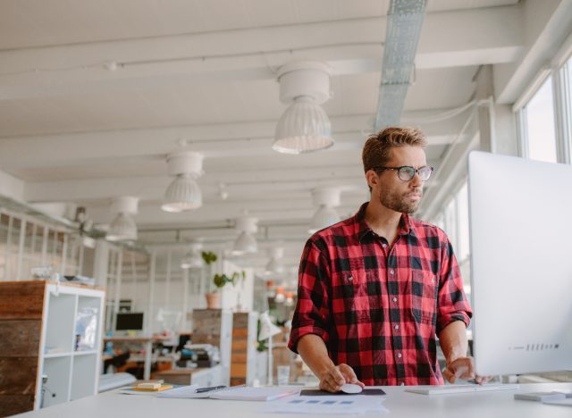 man typing at standing desk