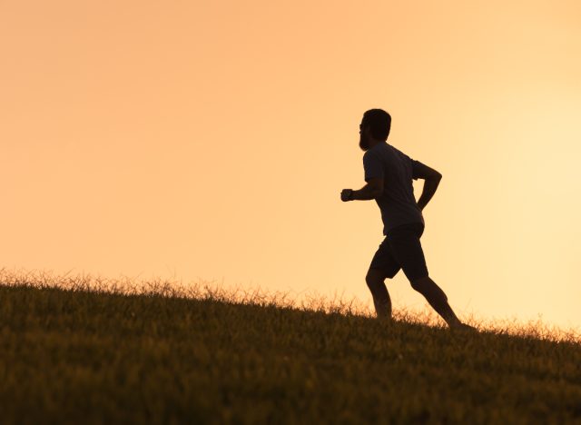 man's silhouette running at sunset up hill