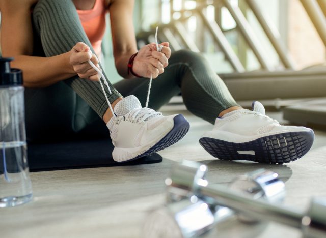 woman tying training shoes in gym