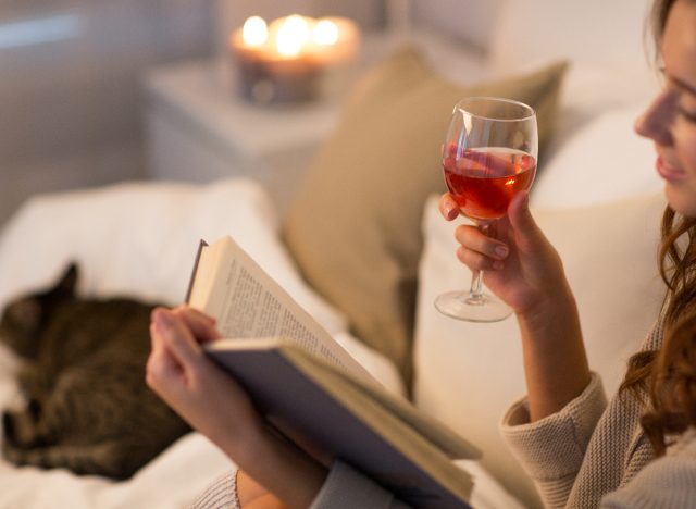 woman drinking wine and reading in bed