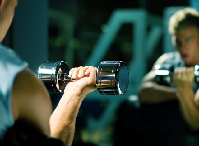 man lifts dumbbell in mirror