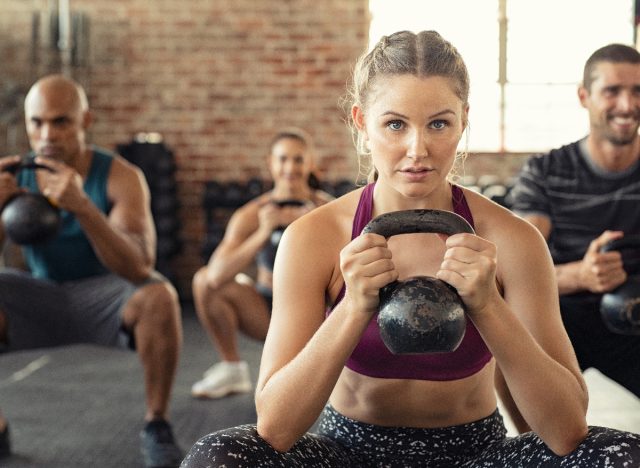 woman holds kettlebell in squat while in exercise class
