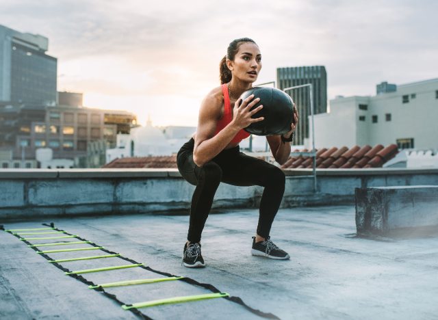 woman squats with medicine ball to burn fat fast