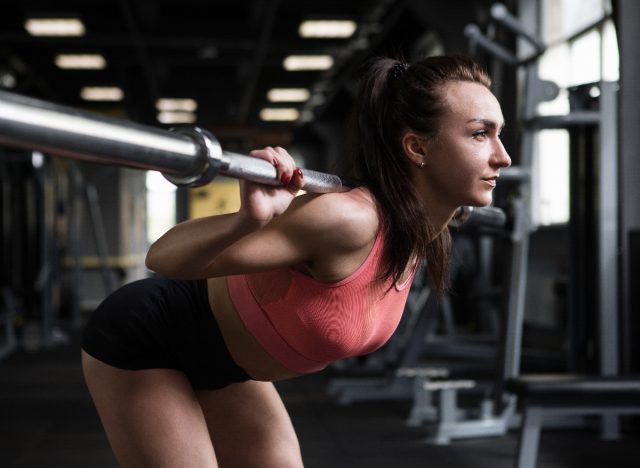 woman performing good morning exercise with barbell