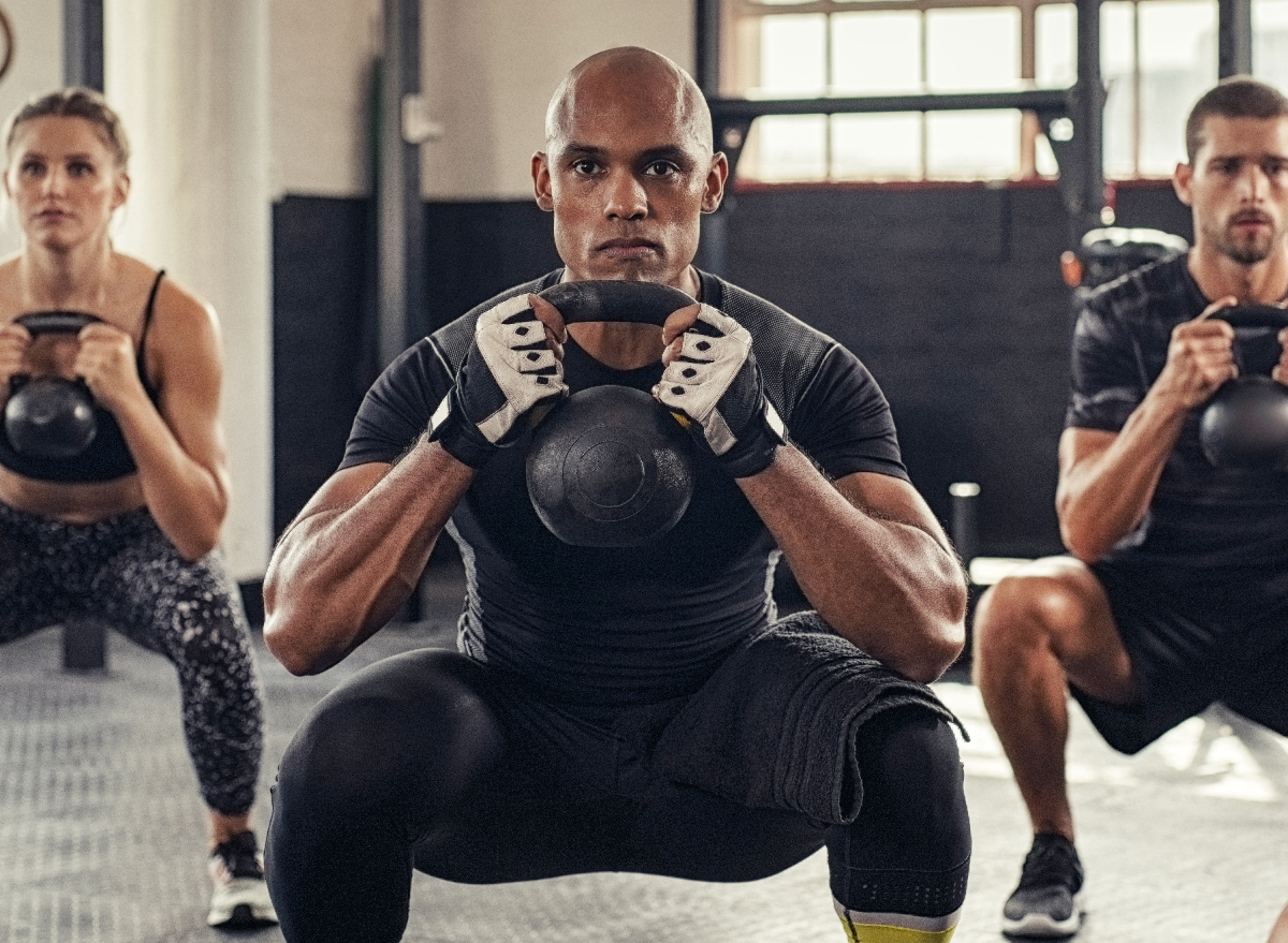 man doing kettlebell workout in group class