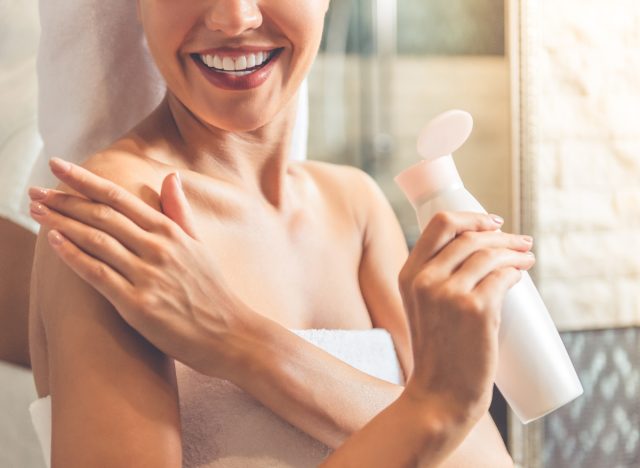 woman applying lotion to arm after shower