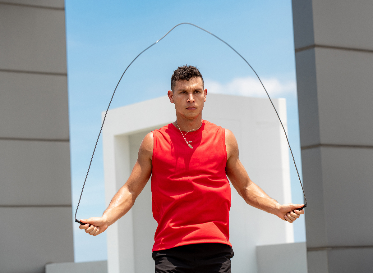 fit man in red tank top doing jump rope exercise