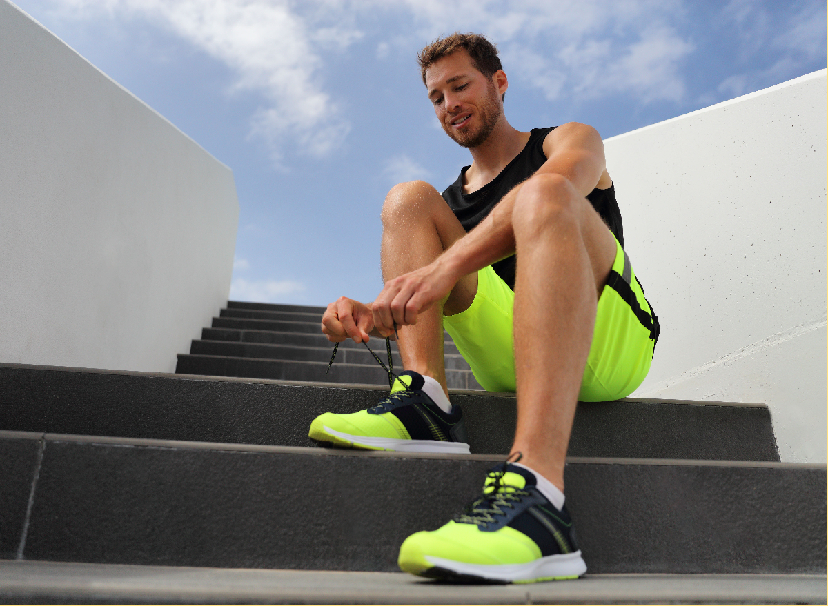 man tying bright green sneakers before running