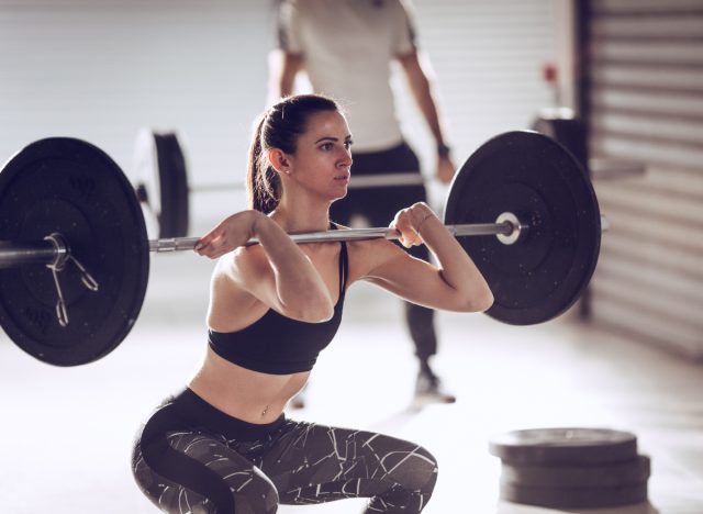 woman doing front squat with barbell at gym