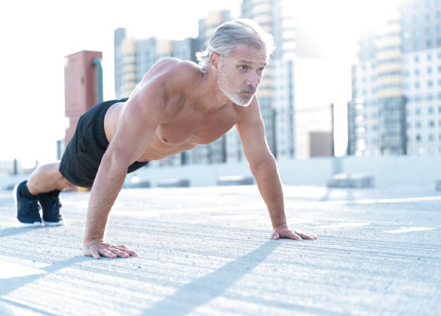 man in his 40s performs a pushup outside