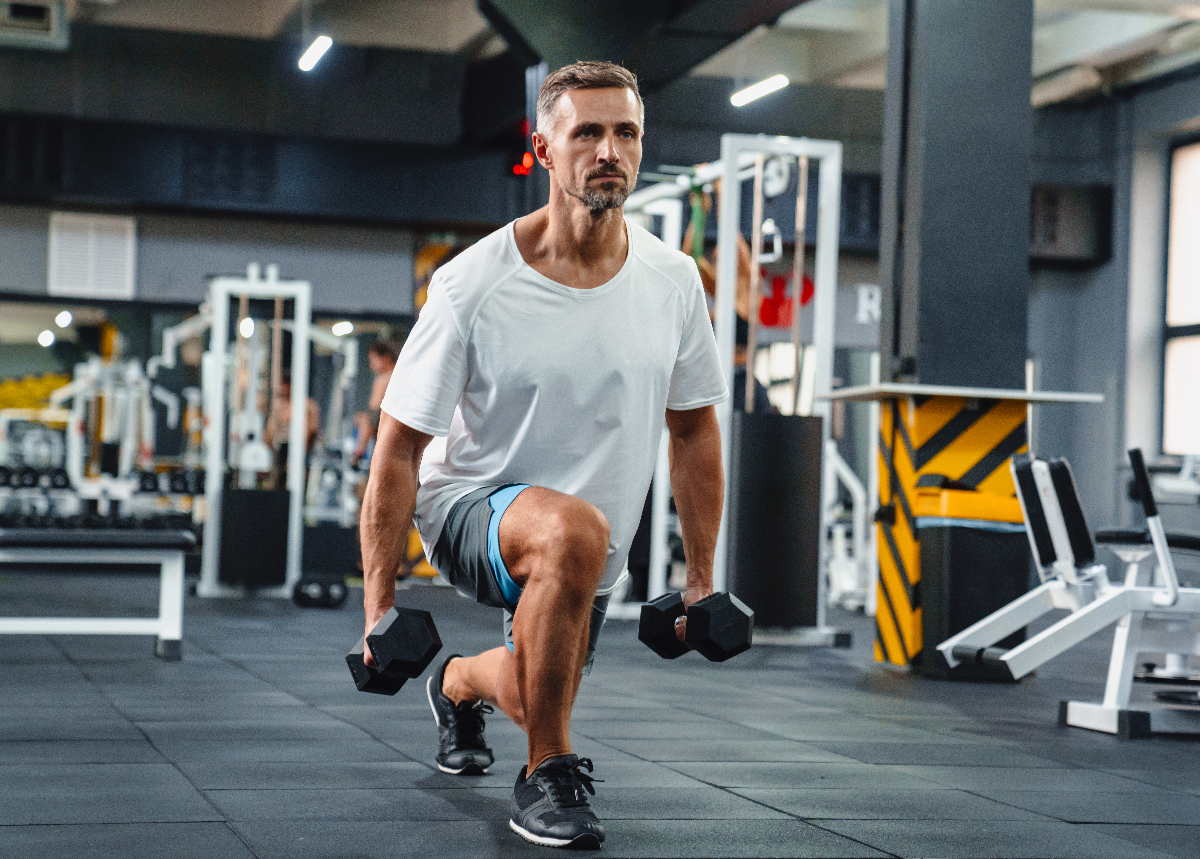 man doing a dumbbell squat in gym