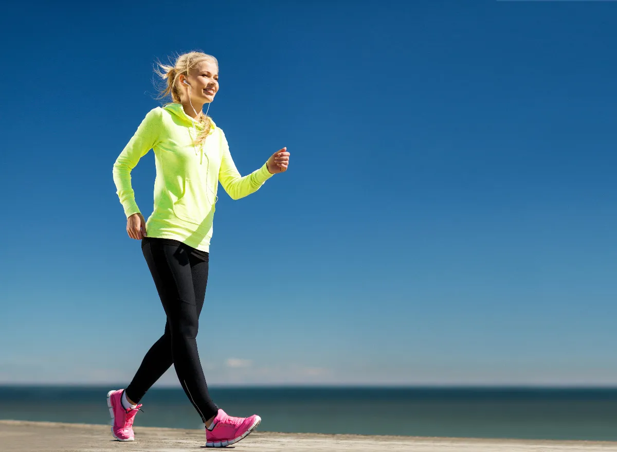 woman dressed in bright colors doing walking workout along beach