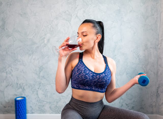 woman sipping wine while stretching / working out