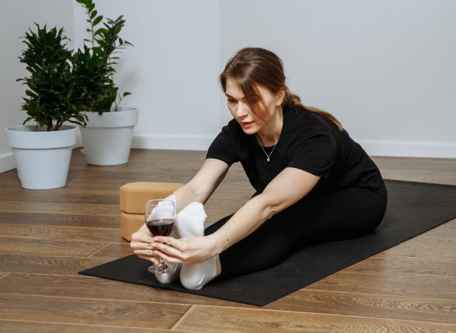 woman does wine yoga while stretching on mat while doing on-demand workout classes