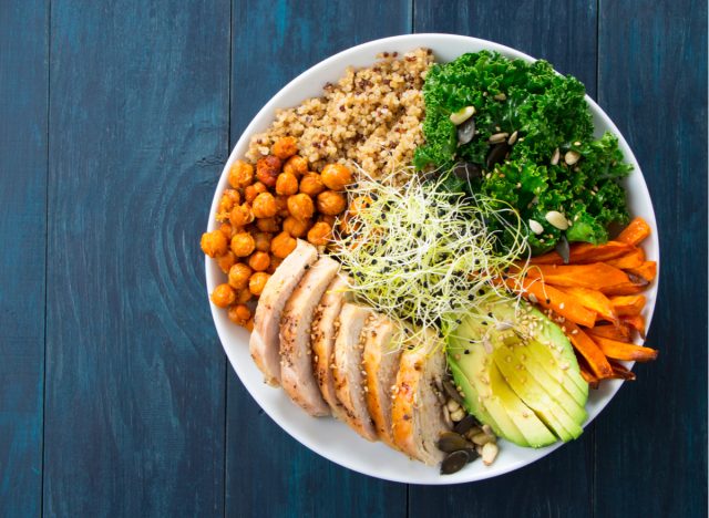 buddha bowl with kale, chickpeas, quinoa, chicken, avocado, and carrots
