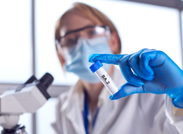 Female Lab Research Worker Wearing PPE Holding Test Tube Labelled BA.2