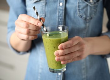holding a green smoothie with a straw