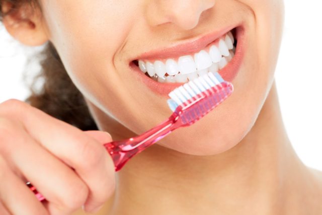 Smiling woman brushing her teeth