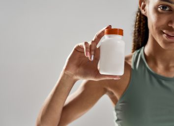 woman holding bottle of supplements after exercise