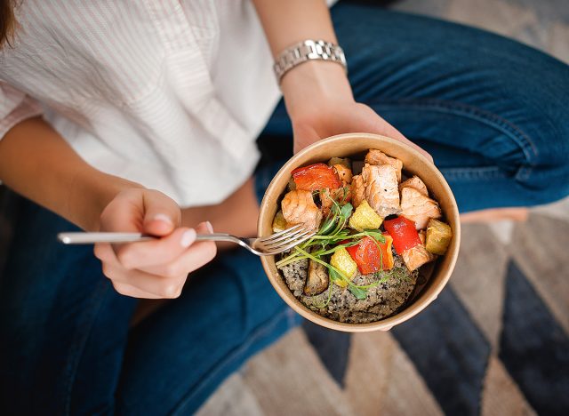woman eating bowl with salmon and healthy superfood