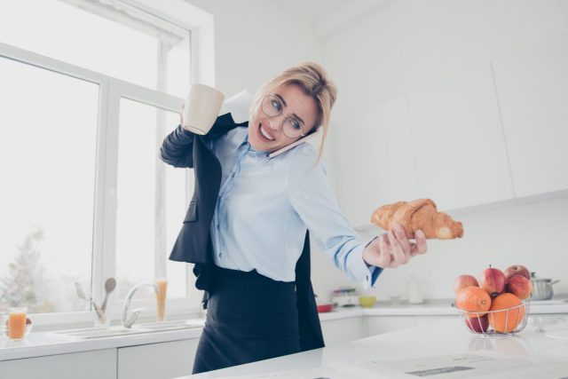 woman rushing, talking on the phone, and holding a croissant