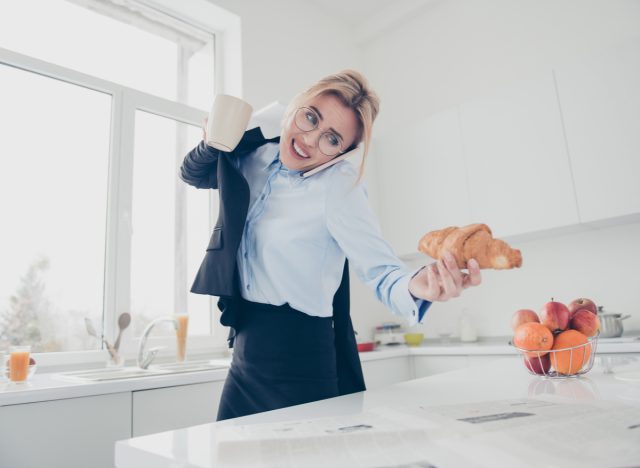 woman rushing, talking on the phone, and holding a croissant