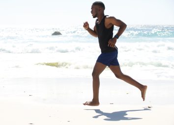 fit man running barefoot on beach