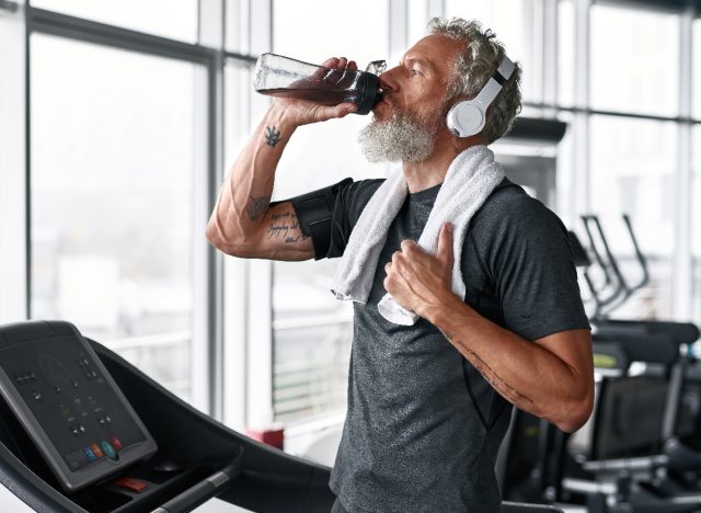 mature man drinking water while exercising