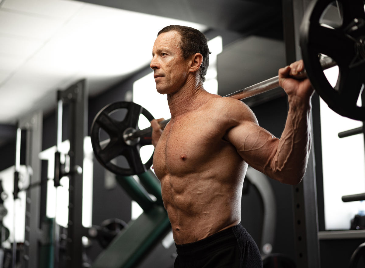 senior man squatting at gym with barbell