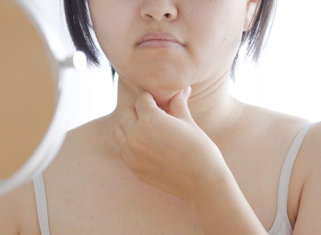 woman doing chin exercise in the mirror