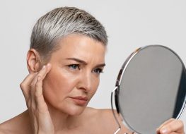 mature woman looking in mirror at aging facial skin