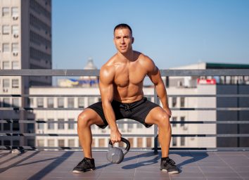 man doing kettlebell exercise on rooftop