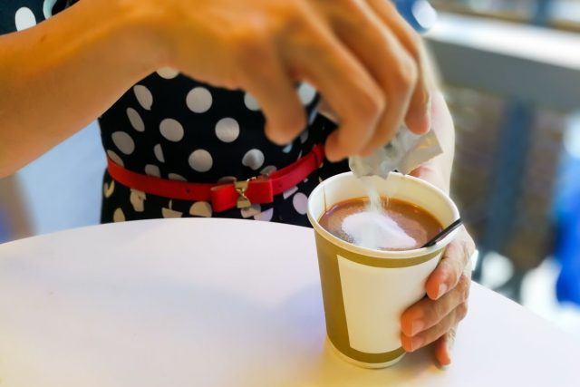 Mujer vertiendo azúcar en el café