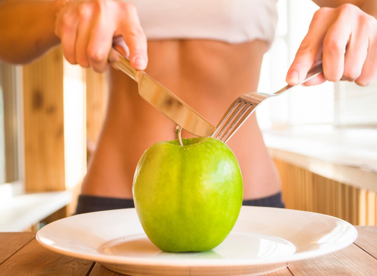 Woman Cutting Green Apple with Fork and Knife