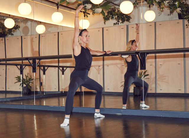 trainer demonstrating barre workout to get rid of PMS symptoms