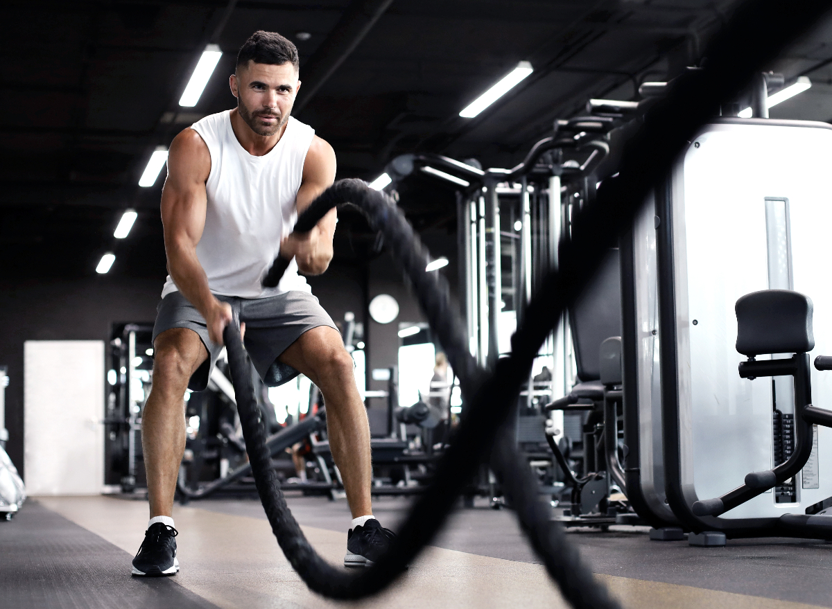 man doing battle rope hiit exercise in gym