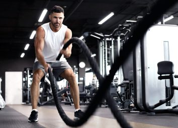 man doing battle rope hiit exercise in gym