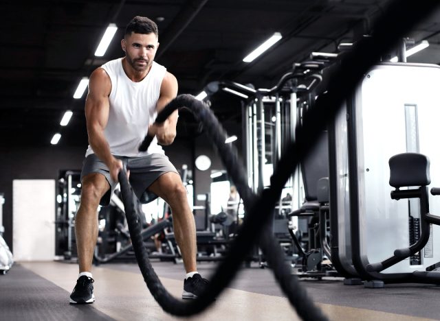 мъж прави упражнение с бойно въже във фитнес залата