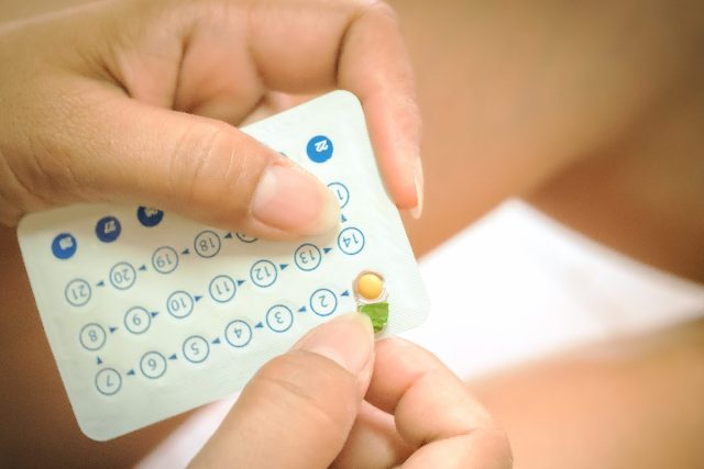 close up hands opening birth control package