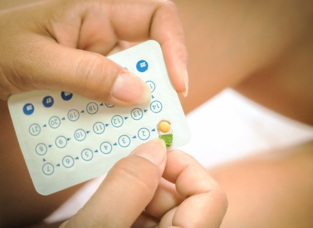 close up hands opening birth control package