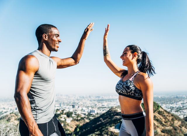 fit couple works out together and shares a high five on top of hike