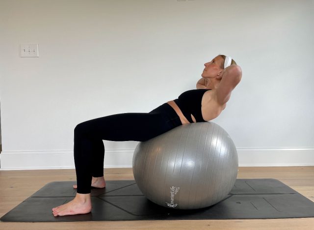 trainer demonstrating crunch stability ball exercise to shrink belly fat