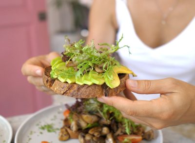 eating whole grain toast with avocado and sprouts