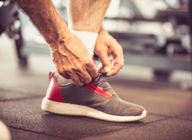 closeup elderly man tying sneaker in gym