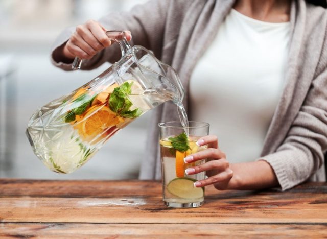 woman pouring water infused with fruit